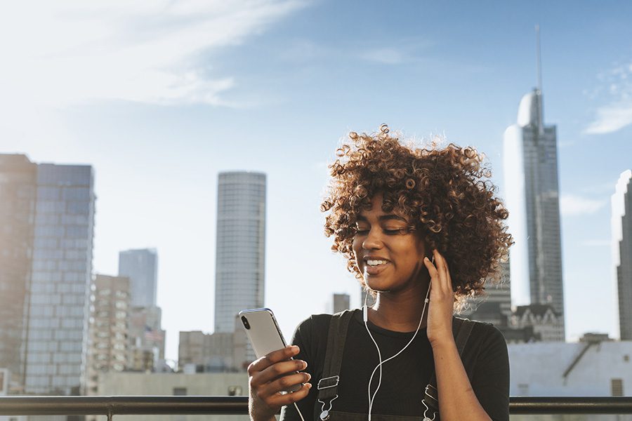 Video Library - Young Woman Watching Videos On Her Phone With The Skyline In The Background